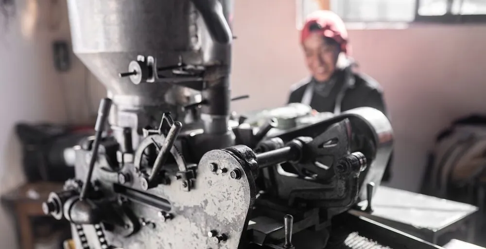 A man standing infront of a machine making tortillas, the image has been used to illustrate a blog about A Lead Generation Machine
